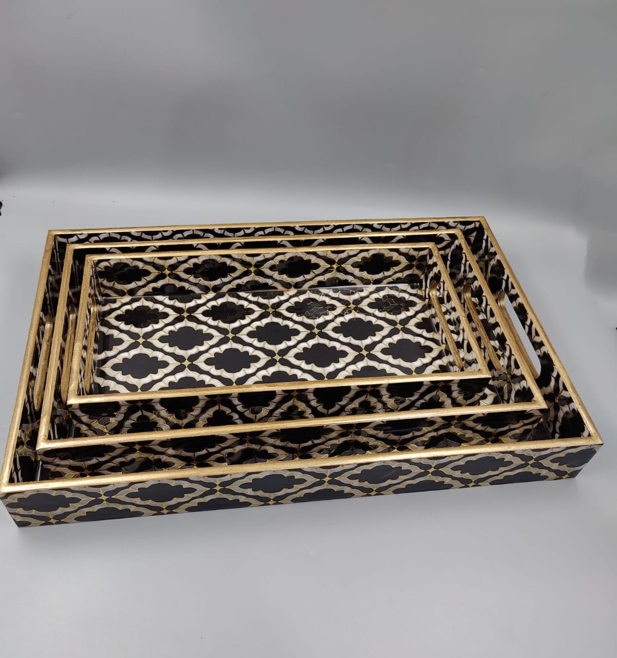 Handcrafted decorative wooden serving tray set with black and gold geometric pattern.