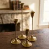 A premium set of four staggered-height vintage brass taper candle holders by OneTrend.